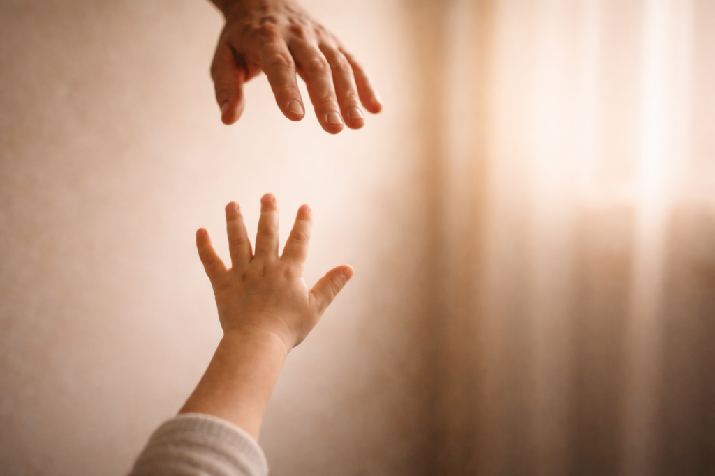 Cause della dipendenza affettiva: mano di bambino che si protende verso una mano adulta non completamente raggiungibile, metafora dell’attaccamento insicuro