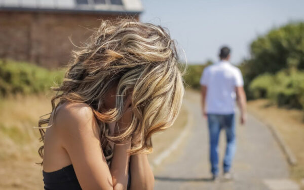 Donna in crisi emotiva mentre un uomo si allontana su un sentiero, simbolo del disturbo borderline