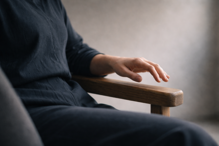 Psicoterapia psicodinamica: mano sospesa su bracciolo in luce naturale, gesto che riflette il momento in cui un contenuto inconscio diventa riconoscibile nel processo terapeutico